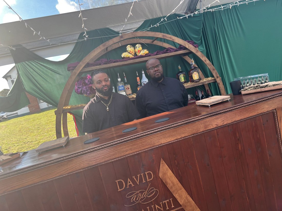 Two bartenders behind a wooden event bar
